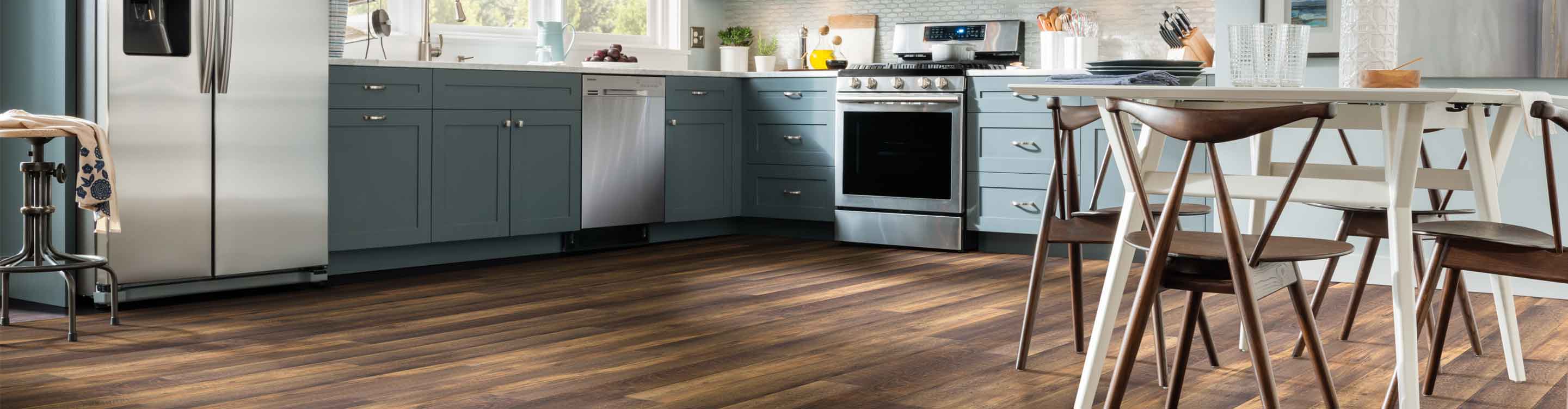 wood-look vinyl flooring in kitchen with blue cabinetry, white table and wood accents